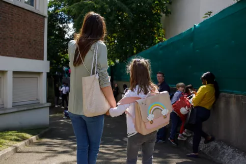 Une maman et sa fille dans la cour de récréation, de dos