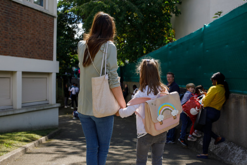Une maman et sa fille dans la cour de récréation, de dos
