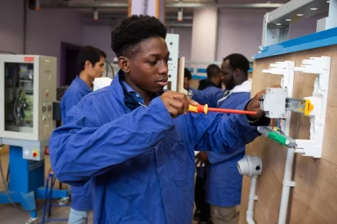 Jeune en formation électricité en plein travail sur un plateau technique
