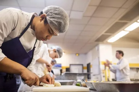 Un jeune en formation en train de cuisiner dans la cuisine d'application de l'école