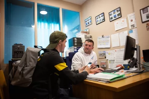 Un éducateur et un jeune à un bureau discutant