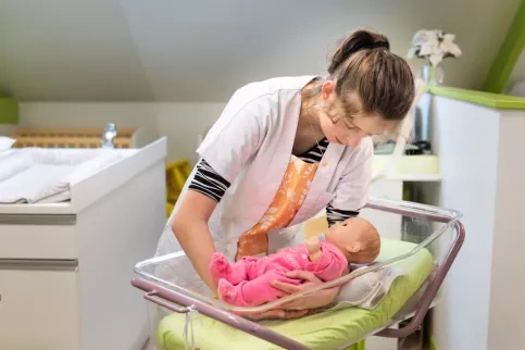Jeune fille en formation service à la personne posant un bébé dans un berceau