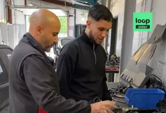 Nesradine, formateur en mécanique automobile explique quelque chose à un jeune en formation