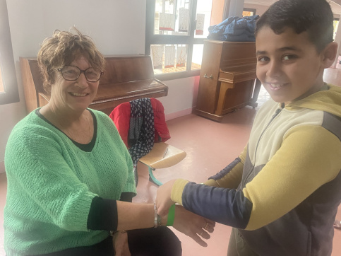 Un élève mettant un bracelet vert à son enseignante