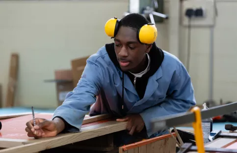 Jeune en formation menuiserie travaillant du bois