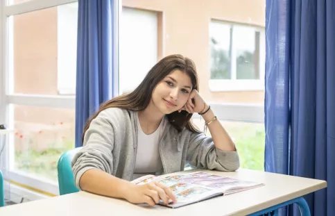 Jeune fille assise à un table de cours, souriante