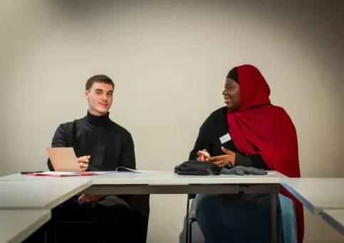 Un jeune homme discutant avec une jeune femme, tous les deux participants au bootcamp Musique