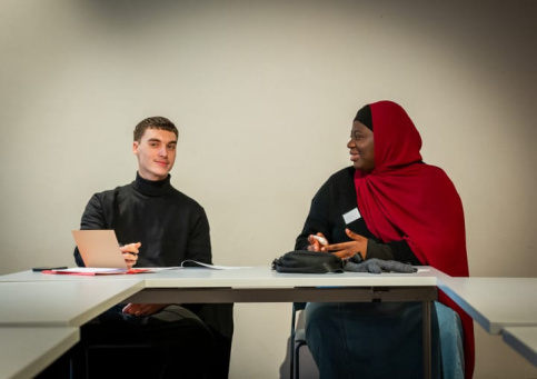 Un jeune homme discutant avec une jeune femme, tous les deux participants au bootcamp Musique