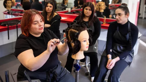 Formatrice de CAP coiffure expliquant à des jeunes une technique de coiffure