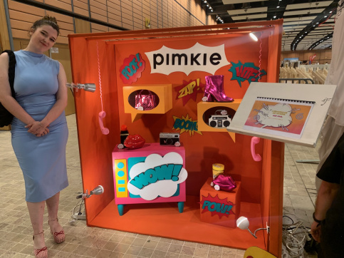 Une jeune en formation Marchandisage visuel devant sa vitrine pour les MAF