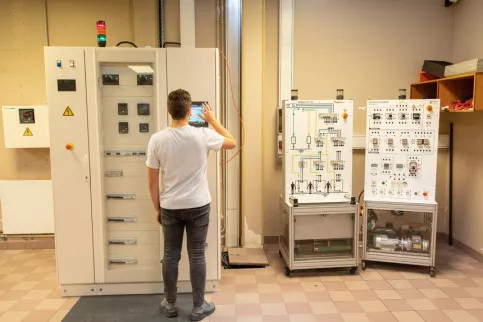 Jeune en formation électrotechnique travaillant sur un plateau technique