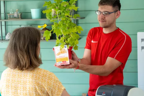 Jeune en formation TCVUJ vendant une plante à une dame