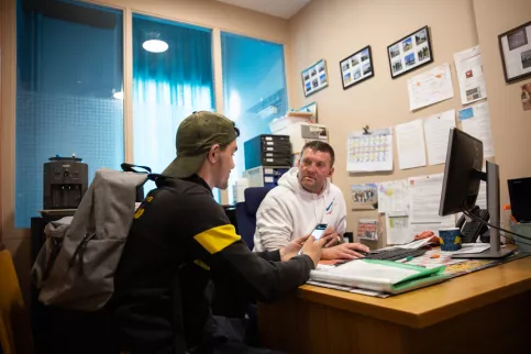 Un éducateur et un jeune à un bureau discutant