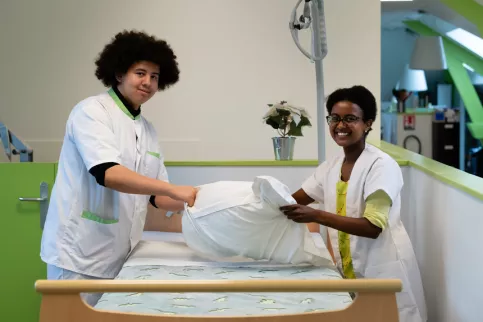 Deux jeunes en formation service à la personne changeant les draps d'un lit