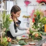 Une jeune en formation en fleuristerie en train de réaliser un bouquet