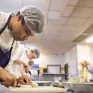 Un jeune en formation en train de cuisiner dans la cuisine d'application de l'école