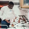 Jeune homme dressant des assiettes de desserts