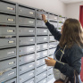 Jeune fille qui prend ses lettres dans une boîte aux lettres