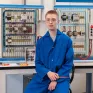 Jeune en formation électricité posant devant son plateau technique de formation