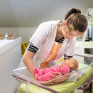 Jeune fille en formation service à la personne posant un bébé dans un berceau
